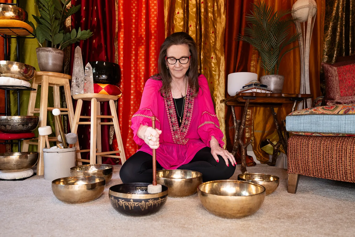 Dorothy Tannahill-Moran seated on the floor playing a brass singing bowl